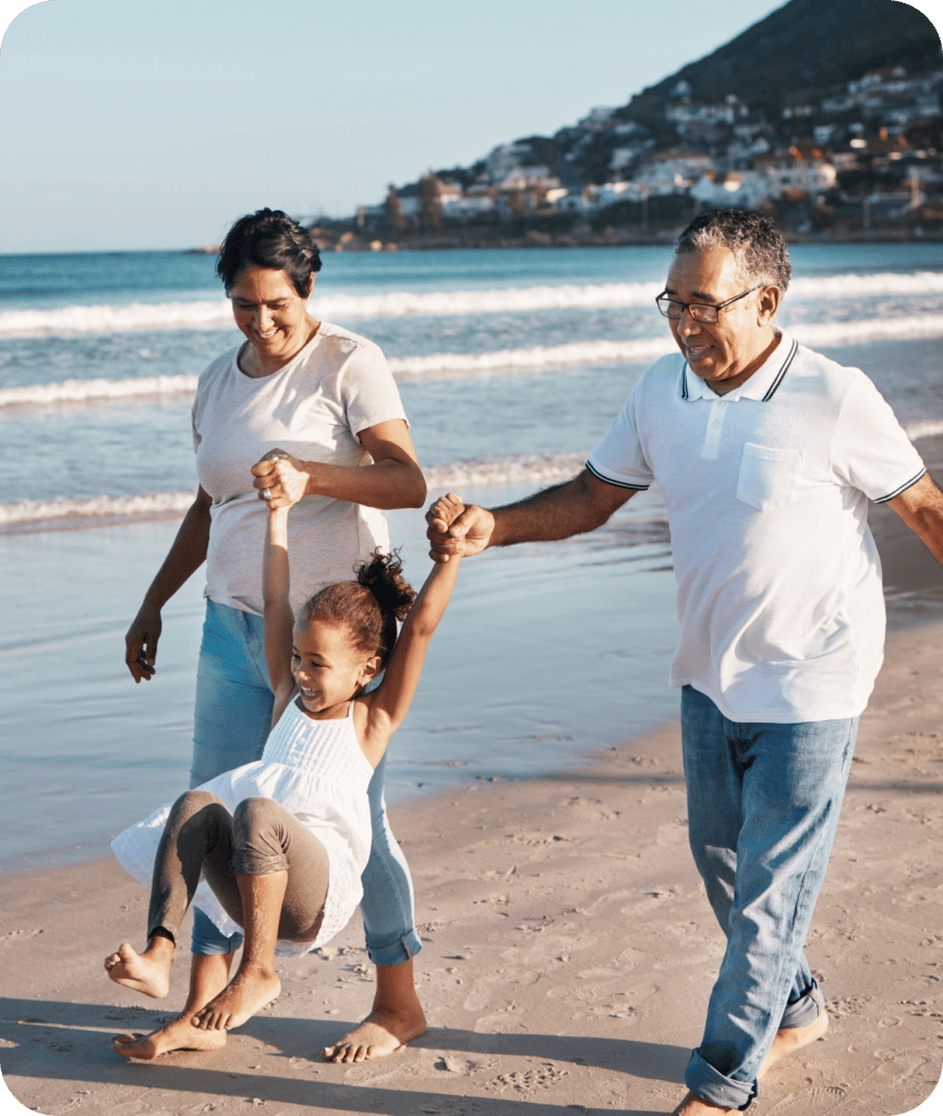 little girl playing on the beach with her grandparents